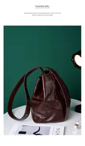 Detailansicht der glänzenden Bucket Bag aus Leder in Dunkelbraun mit breitem Riemen