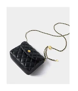 Detailed macro of black quilted leather bag with gold floral buckle and chain strap