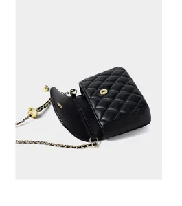 Detail of black quilted leather shoulder bag with gold chain and adjustment ball