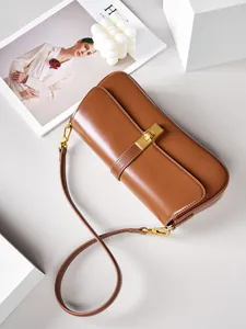 Brown leather baguette shoulder bag with gold buckle shown from a 45-degree angle view