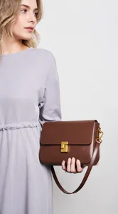 Detail of a brown leather shoulder bag featuring a vintage gold square metal clasp and strap