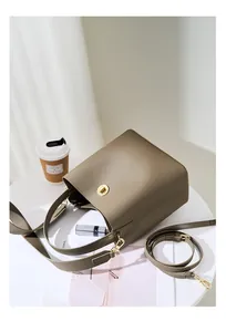 Vista dettagliata di una borsa a secchiello in pelle taupe con hardware dorato su tavolo