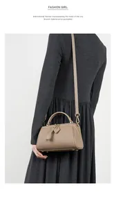 Detail view of taupe lychee grain leather Boston bag with gold hardware and shoulder strap