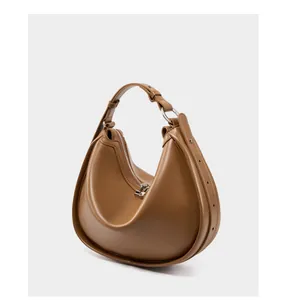 Detail view of the caramel leather crescent bag showing silver hardware and smooth texture