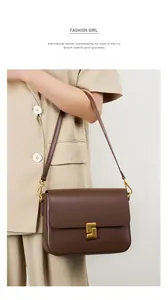 Detail of dark brown leather crossbody bag with golden geometric lock on cream blazer