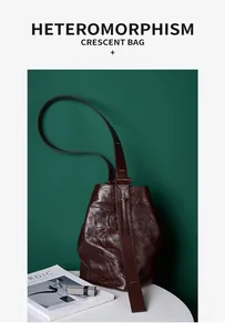 Detail einer dunkelroten Halbmond-Tasche aus Faltenleder auf grünem Hintergrund