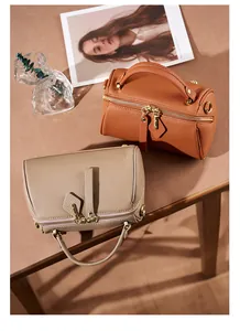 Detail of leather Boston bags in brown and taupe with gold zippers and pebble texture