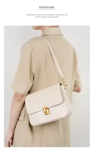 Model wearing a cream leather shoulder bag with a gold geometric clasp and sleek strap