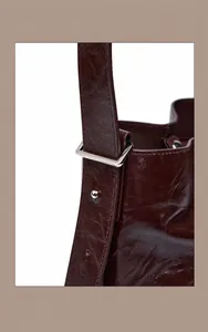 Detail des Nietriemens an einer dunkelbraunen Vintage-Lederbeuteltasche mit Silberschnalle