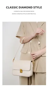 Close-up of cream leather shoulder bag featuring a square gold metal clasp and adjustable strap