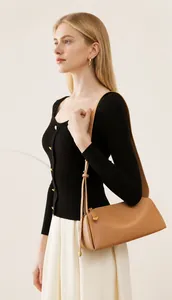 Détail d'un sac bandoulière en cuir marron de qualité avec texture fine et finitions dorées