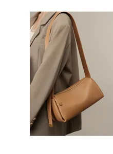 Détail d'un sac polochon en cuir minimaliste marron chameau avec large bandoulière