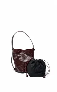 Detail der burgunderroten Leder-Eimertasche mit schwarzem Kordelzug-Innenbeutel