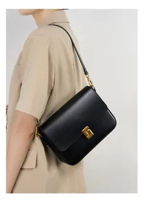 Detail of matte black leather shoulder bag with a square gold geometric metal buckle
