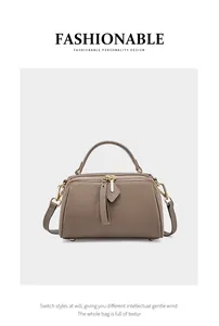 Detailed view of brown lychee grain leather Boston bag with gold zippers and charms