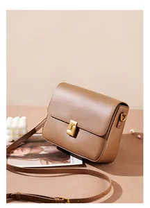 Detailed close-up of brown leather bag with elegant matte gold geometric buckle clasp