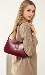 Détail du sac à bandoulière en cuir bordeaux avec boucle dorée en forme de gourde