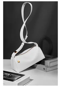 Gros plan du sac oreiller en cuir blanc avec zip doré et bandoulière large réglable