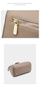 Close-up of pebble leather texture and protective golden metal studs on Boston bag base