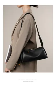 Détail du sac bandoulière en cuir noir avec ornements dorés en forme de cœur et sangle chic
