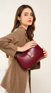 Vue mannequin d'un sac sous le bras en cuir rouge foncé avec boucle dorée élégante