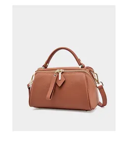 Detail of tan lychee grain leather Boston bag with dual zippers and gold hardware
