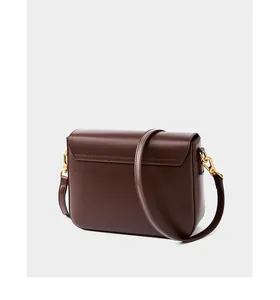 Detail view of the back of a dark brown leather shoulder bag with gold metal hardware