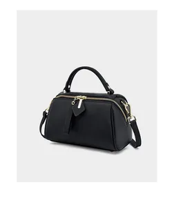 Detail of black pebbled leather Boston bag with gold zipper and removable shoulder strap