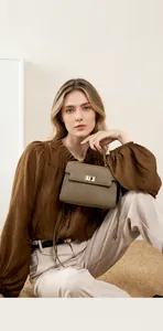 Détail du sac en cuir texturé kaki avec poignée, fermoir rotatif en métal et bandoulière
