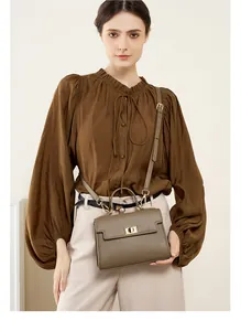 Détail du sac en cuir marron avec fermoir tournant doré et texture grainée fine