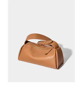 Détail du sac polochon en cuir caramel avec large bandoulière et boucle dorée