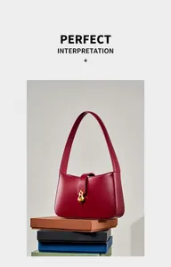 Détail du sac sous le bras en cuir rouge vin avec boucle dorée sur coffrets cadeaux