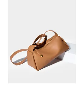 Détail du sac bandoulière en cuir caramel avec zip doré et bandoulière réglable sur blanc