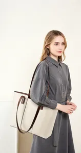 Sac cabas minimaliste en cuir crème avec anses brunes présenté sur un mannequin élégant
