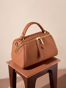 Brown lychee leather Boston bag with gold hardware on minimalist stool, 45-degree view
