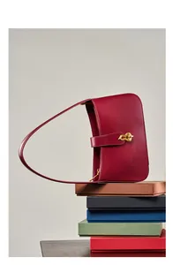 Détail du sac à bandoulière en cuir rouge avec boucle dorée sur des boîtes colorées