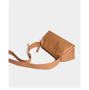 Détail du cuir de couleur caramel et de la large bandoulière d'un sac oreiller chic