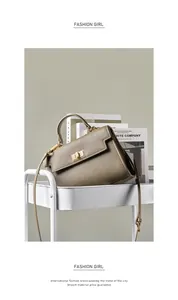 Détail d'un sac bandoulière en cuir grainé kaki avec fermoir doré sur un support