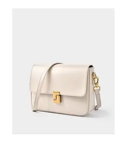 Detail of matte gold geometric clasp on an ivory leather crossbody handbag with smooth texture