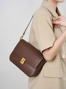 Classic dark brown leather shoulder bag with vintage gold clasp on beige blazer