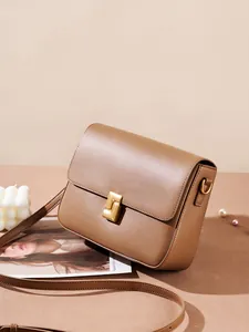 Vintage brown leather crossbody bag with elegant gold buckle on minimalist background