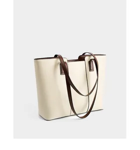 Détail du sac cabas en cuir crème avec bandoulières marron foncé et texture grainée