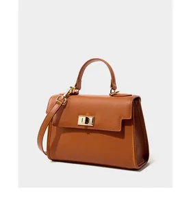 Détail d'un sac à main en cuir marron montrant le grain fin et le fermoir tournant doré