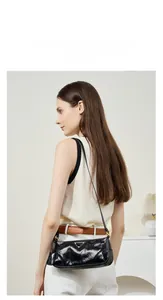 Detail of model wearing a black oil-wax leather shoulder bag with triangle logo plaque