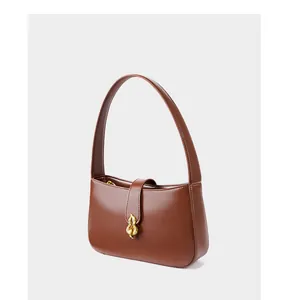 Gros plan du sac à main en cuir marron foncé avec une boucle en métal doré en forme de flamme