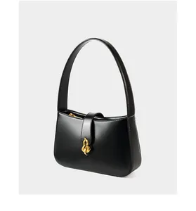 Gros plan d'un sac demi-lune en cuir brillant noir avec boucle dorée artistique