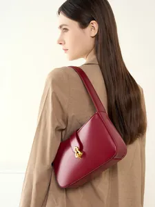 Sac sous le bras élégant en cuir bordeaux avec boucle dorée porté par un modèle