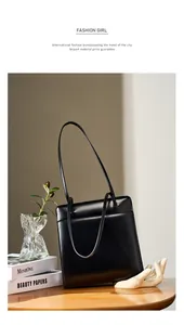 Sac fourre-tout minimaliste en cuir noir avec fines bretelles sur une table en bois