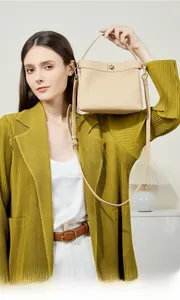 Close-up of beige leather underarm bag with gold metal lock and fine litchi grain texture