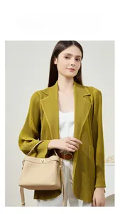 Detail of beige lychee leather handbag with gold metal clasp on a pleated cardigan outfit